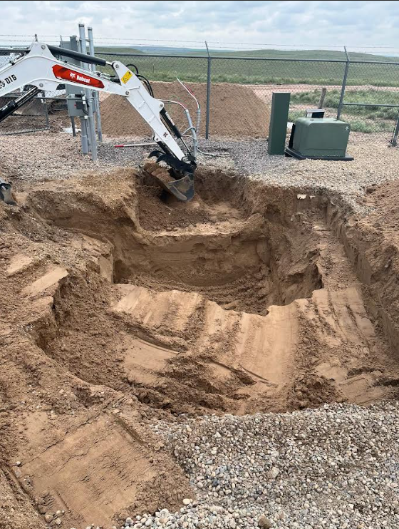 Compact excavator completing precision excavation near utility equipment