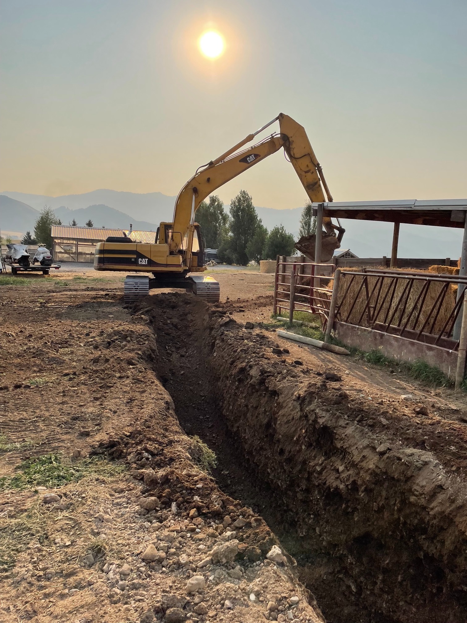 Excavator trenching a waterline on a Wyoming ranch